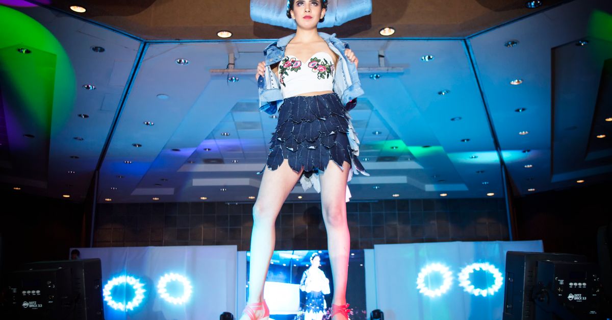 Chic fashion model striking a pose on a vibrant runway stage.